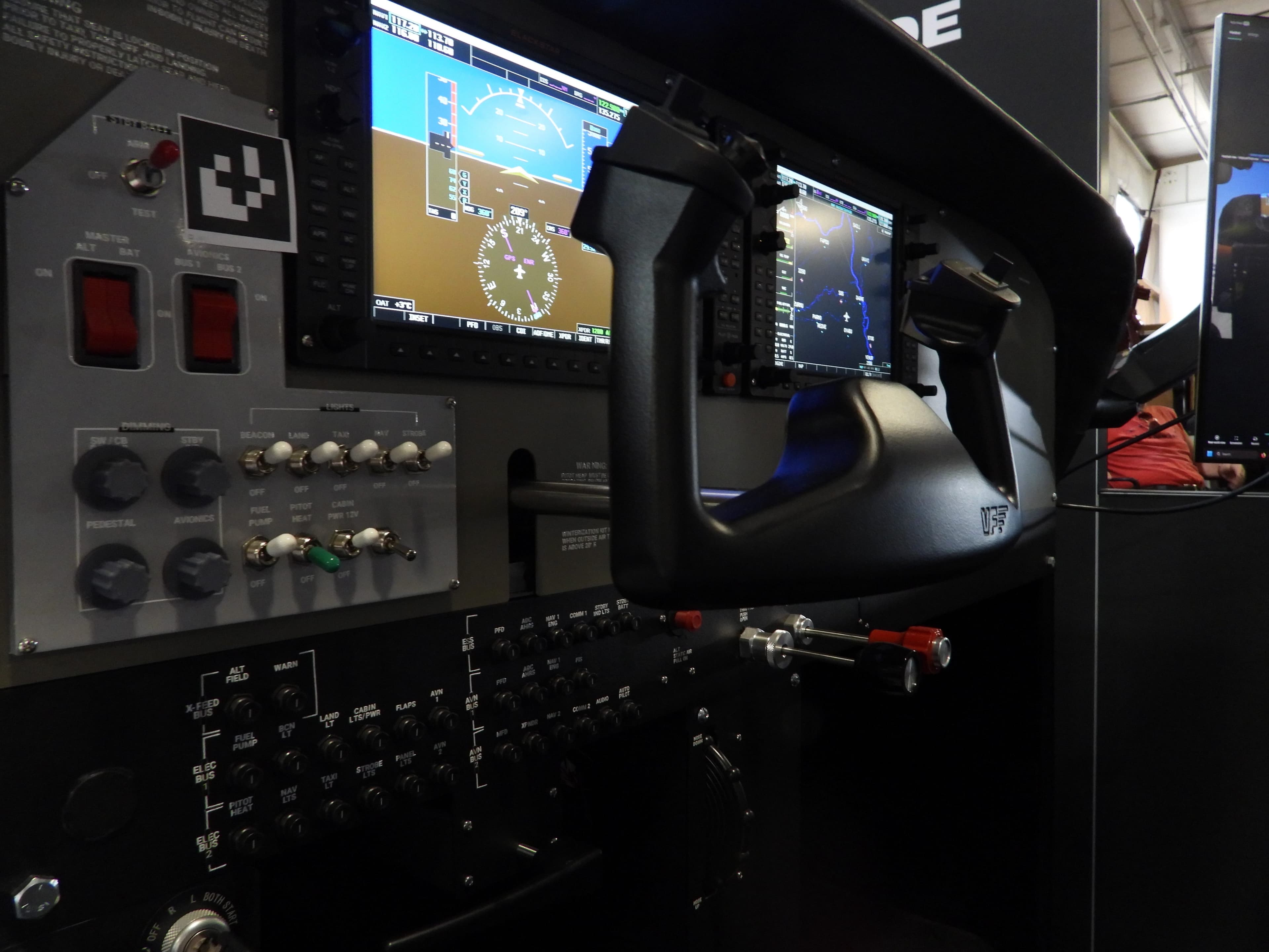 Eclipse AATD cockpit panel with glass avionics displays, control stick, and physical switches